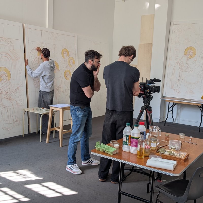 Vue d'ensemble de l'atelier, plusieurs paroissiens travaillent sur les icônes grand format.