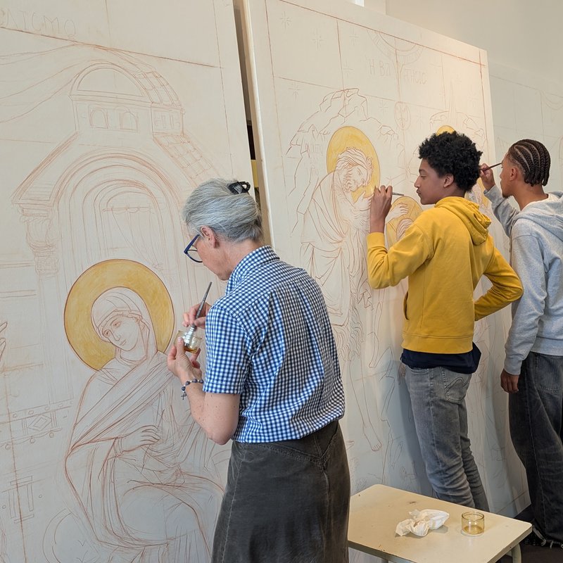 Deux jeunes paroissiens peignent l'icône du Baptême du Christ, accompagnés par l'iconographe.